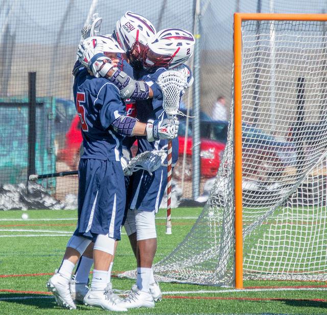 Men's lacrosse players celebrating a goal. Photo by Dustin Cox