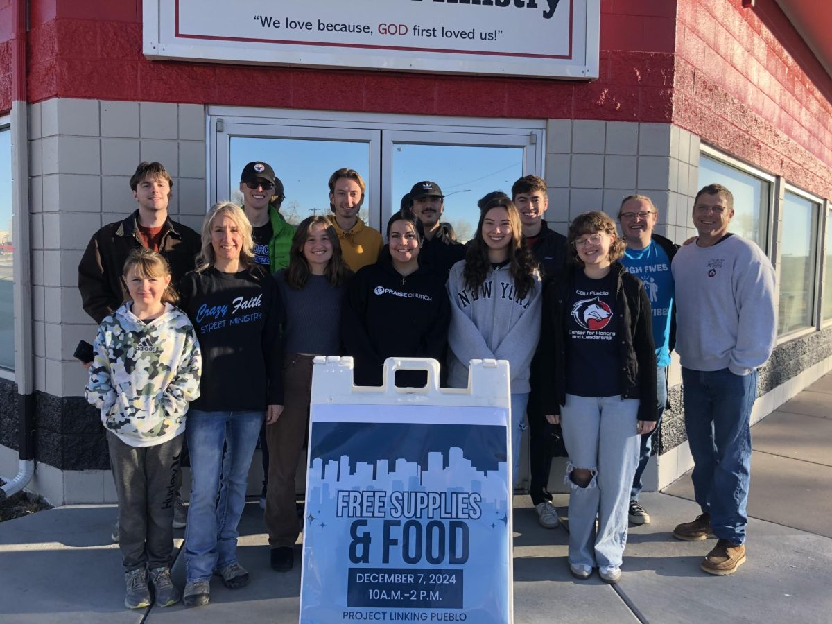 The students gather behind a poster for the event they created to serve those in need in Pueblo. (Photo provided by Project Linking Pueblo).