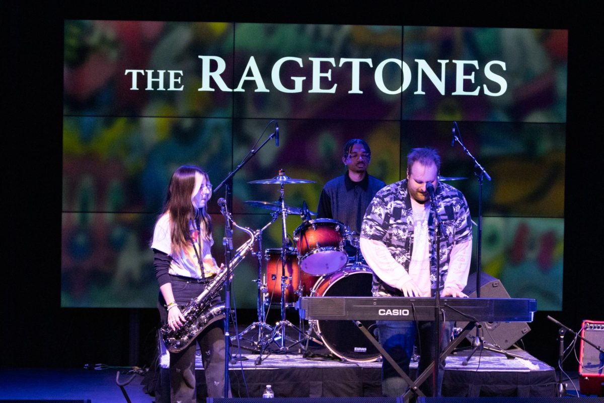 Taryn Tibbs (left) plays the saxophone, Christopher Farris (back middle) plays the drums, and Jesse Hed (right) plays the keyboard and sings during The Ragetones’ performance at Rocky Mountain Rhythm. (Photo by Quinna Rollings)