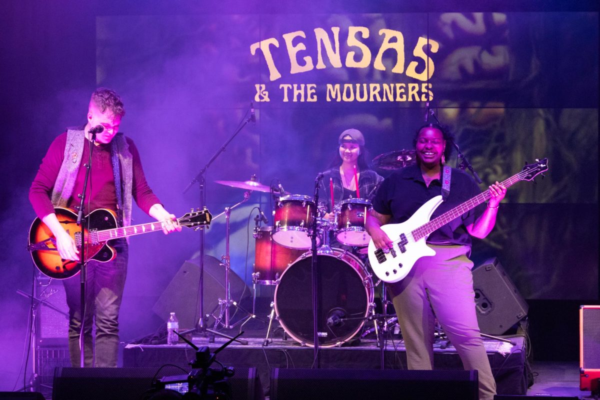 Tensas & The Mourners are shown on stage playing the electric guitar, bass guitar and drums during the group's performance at Rocky Mountain Rhythm, which took place on Feb. 22 in the TV studio at the Buell Communications Center. (Photo by Holly Ward) 
